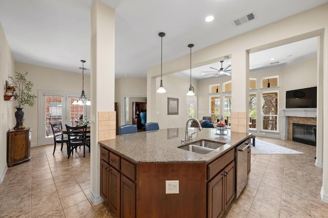 kitchen featuring visible vents, brown cabinetry, open floor plan, a sink, and stainless steel dishwasher