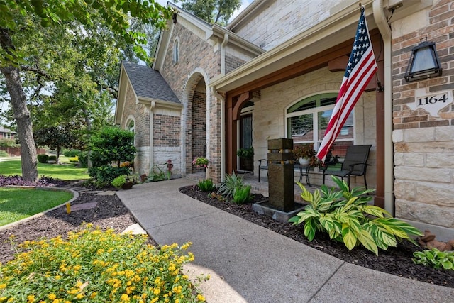 view of exterior entry with a porch and brick siding