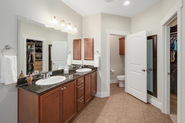 bathroom with toilet, double vanity, a sink, and tile patterned floors