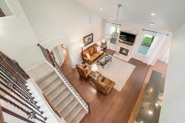 living area with arched walkways, wood finished floors, stairs, a fireplace, and recessed lighting