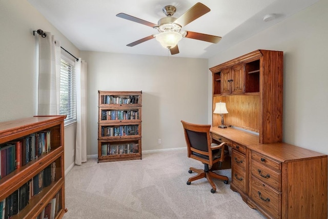 office with baseboards, ceiling fan, built in desk, and light colored carpet