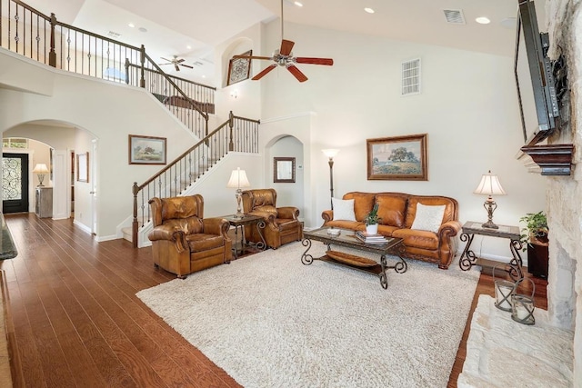 living room featuring arched walkways, hardwood / wood-style flooring, stairs, and visible vents