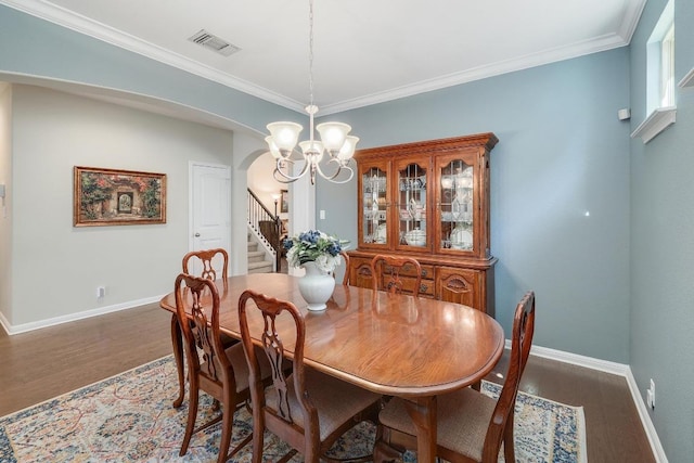 dining area with visible vents, arched walkways, wood finished floors, an inviting chandelier, and stairs