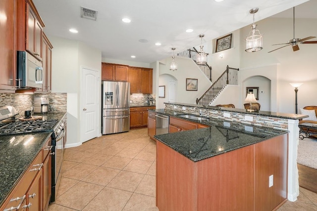 kitchen with visible vents, arched walkways, brown cabinets, stainless steel appliances, and a sink