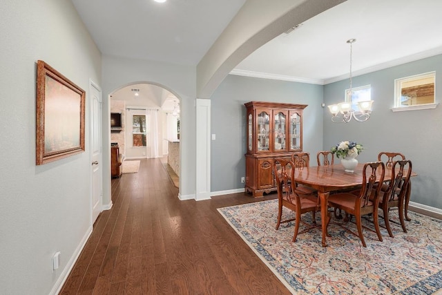 dining area with dark wood-style floors, arched walkways, crown molding, a chandelier, and baseboards