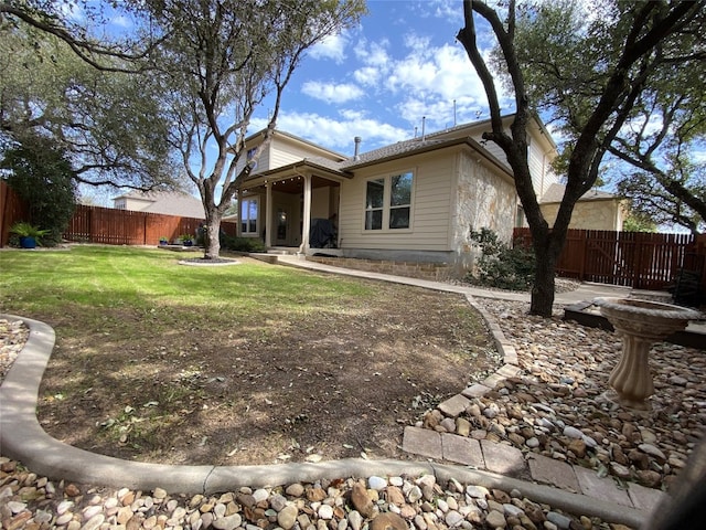 rear view of property with fence and a lawn