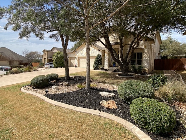 view of front facade with driveway, stone siding, a garage, and fence