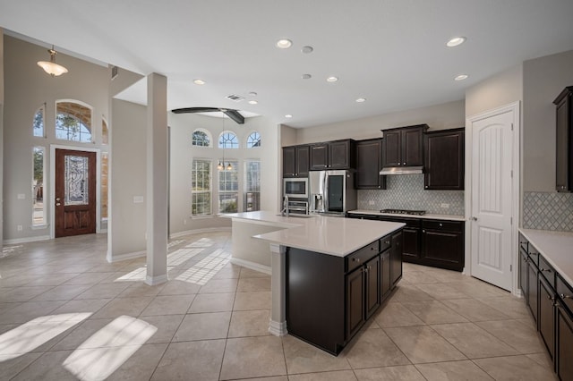 kitchen with light countertops, appliances with stainless steel finishes, light tile patterned flooring, and decorative backsplash