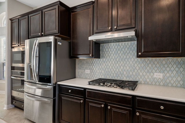 kitchen with stainless steel appliances, tasteful backsplash, light countertops, light tile patterned flooring, and under cabinet range hood