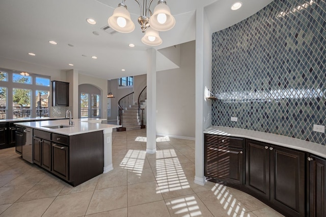 kitchen featuring tasteful backsplash, arched walkways, light countertops, and a sink