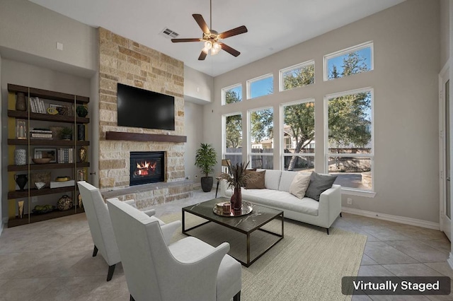 living room featuring ceiling fan, tile patterned flooring, a fireplace, visible vents, and baseboards