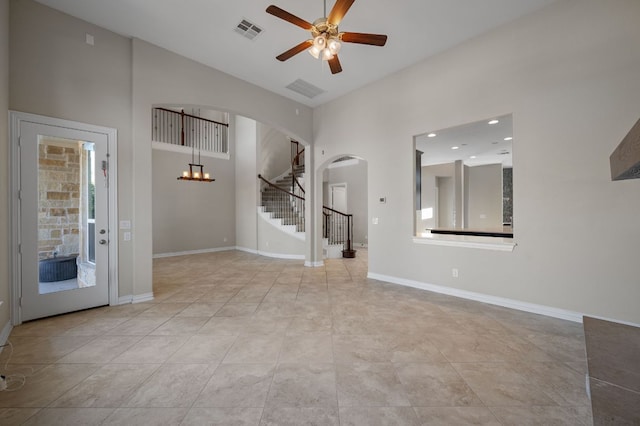 spare room with arched walkways, visible vents, stairway, baseboards, and ceiling fan with notable chandelier