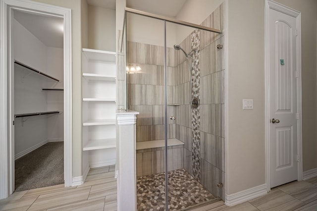 full bathroom featuring a shower stall, baseboards, and a walk in closet