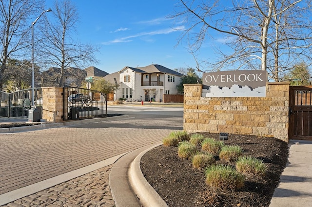 view of street with street lights, curbs, a gated entry, and a gate