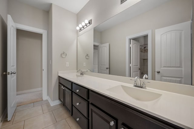 bathroom featuring double vanity, tile patterned flooring, a sink, and baseboards