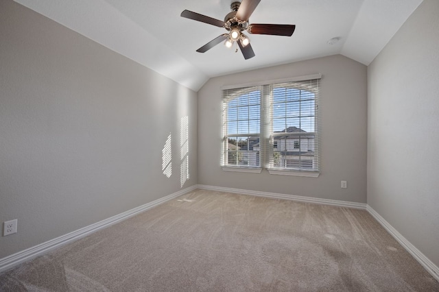 spare room with lofted ceiling, light carpet, a ceiling fan, and baseboards