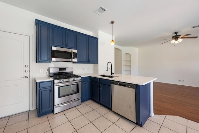 kitchen with light tile patterned floors, arched walkways, appliances with stainless steel finishes, blue cabinets, and a sink