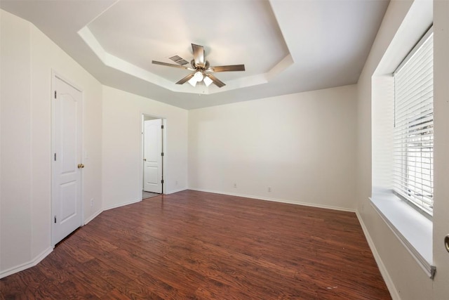 unfurnished bedroom featuring wood finished floors, a raised ceiling, visible vents, and baseboards