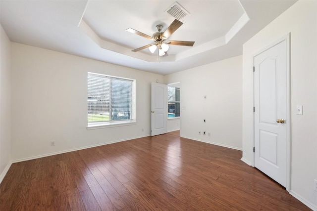 unfurnished room with ceiling fan, wood finished floors, visible vents, baseboards, and a raised ceiling