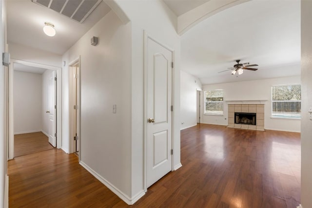 hallway with arched walkways, visible vents, dark wood finished floors, and baseboards