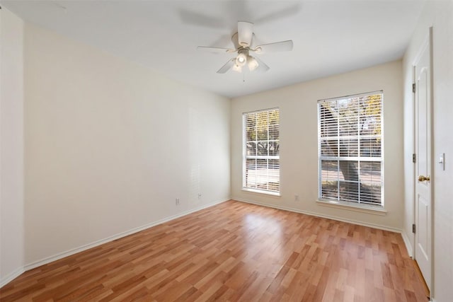 spare room with a ceiling fan, light wood-type flooring, and baseboards