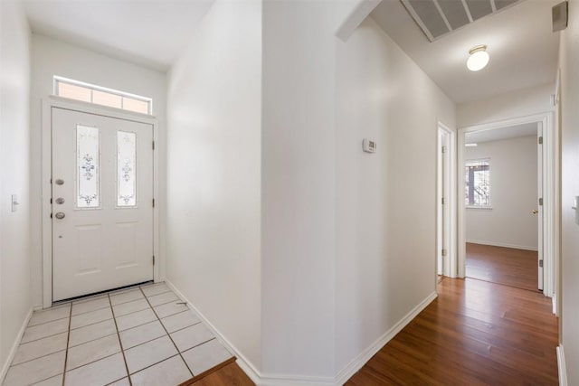 foyer entrance with baseboards, visible vents, and light wood finished floors