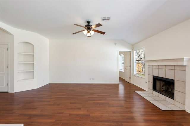 unfurnished living room featuring built in shelves, a fireplace, visible vents, a ceiling fan, and wood finished floors