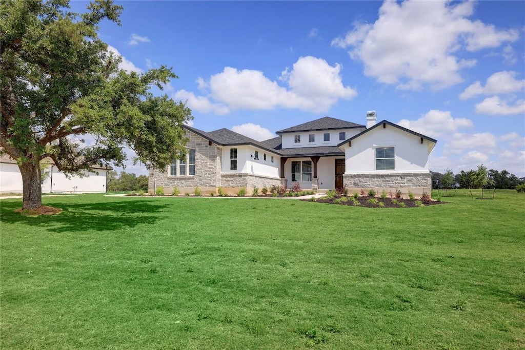 view of front of property featuring stone siding, a front lawn, and stucco siding