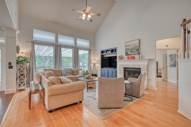 living room featuring high vaulted ceiling, a fireplace, hardwood / wood-style flooring, and a ceiling fan