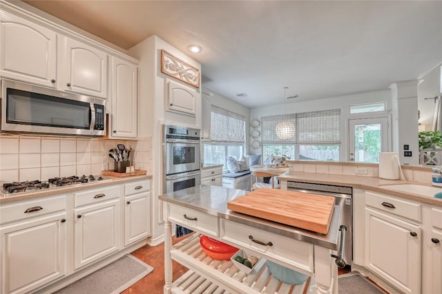 kitchen with light countertops, backsplash, appliances with stainless steel finishes, white cabinetry, and a sink