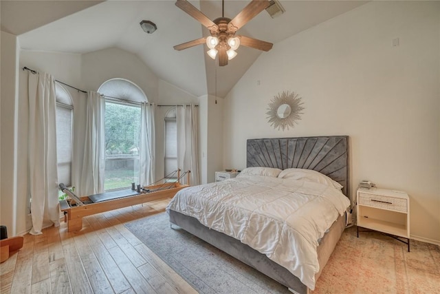 bedroom with a ceiling fan, lofted ceiling, visible vents, and wood finished floors