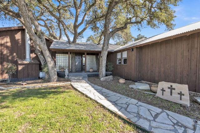 exterior space featuring metal roof and a lawn