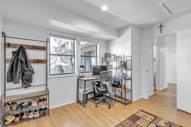 office space with baseboards, attic access, and light wood-style floors