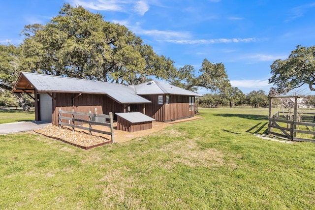 view of yard featuring an outdoor structure, a garage, driveway, and an exterior structure