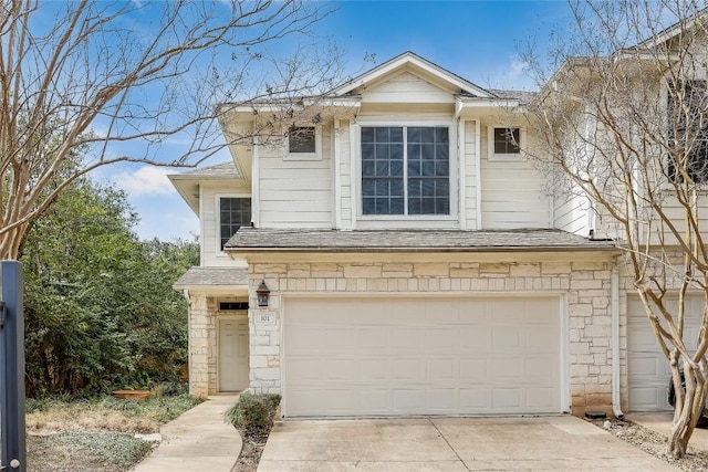 view of front of home with a garage, stone siding, roof with shingles, and driveway