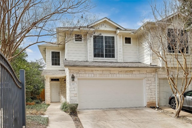 view of front of property featuring stone siding, concrete driveway, a garage, and roof with shingles