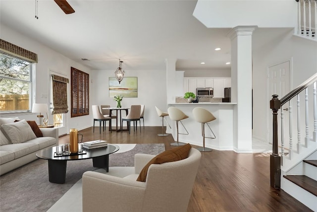 living room featuring stairs, decorative columns, dark wood-style floors, and recessed lighting