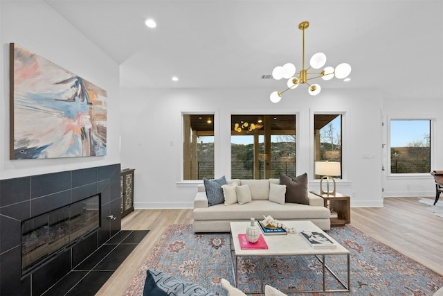 living room featuring wood finished floors, a fireplace, baseboards, recessed lighting, and a chandelier