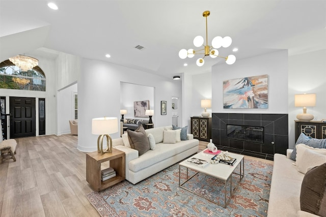 living room featuring light wood-style floors, visible vents, a fireplace, and a chandelier