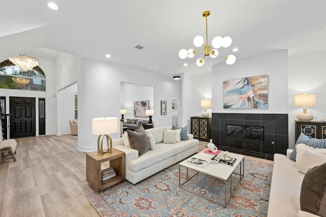 living room featuring an inviting chandelier, visible vents, a fireplace, recessed lighting, and light wood finished floors