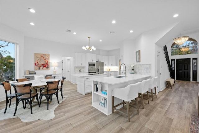 dining area featuring light wood-style flooring, recessed lighting, stairs, and a notable chandelier