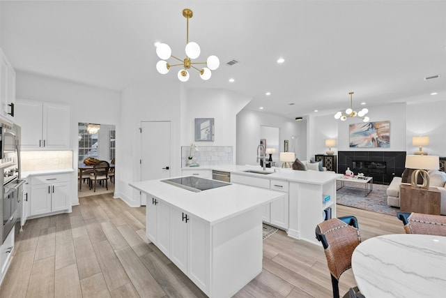 kitchen with open floor plan, a sink, a peninsula, and a chandelier