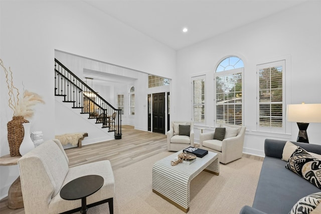 living area with wood finished floors, stairway, baseboards, a high ceiling, and recessed lighting