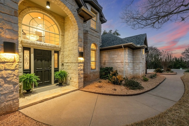 7905 Brightman Ln, Austin, TX 78733 - exterior entry at dusk with stone siding and a shingled roof