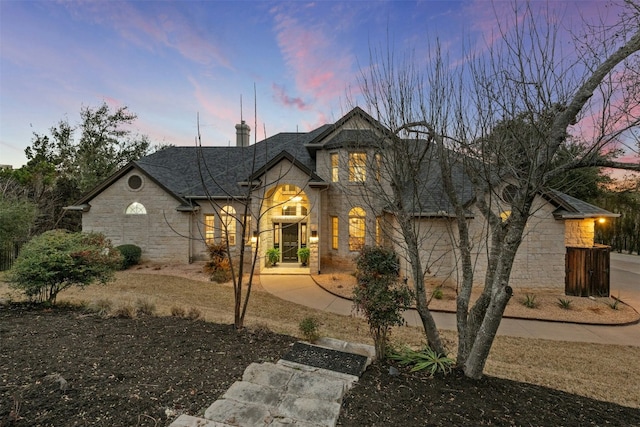 french country style house featuring stone siding and roof with shingles