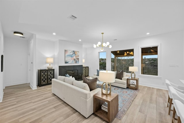 living room with light wood finished floors, a tiled fireplace, and recessed lighting