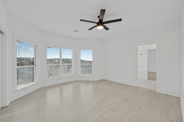 empty room featuring light wood-type flooring, a wealth of natural light, and a ceiling fan