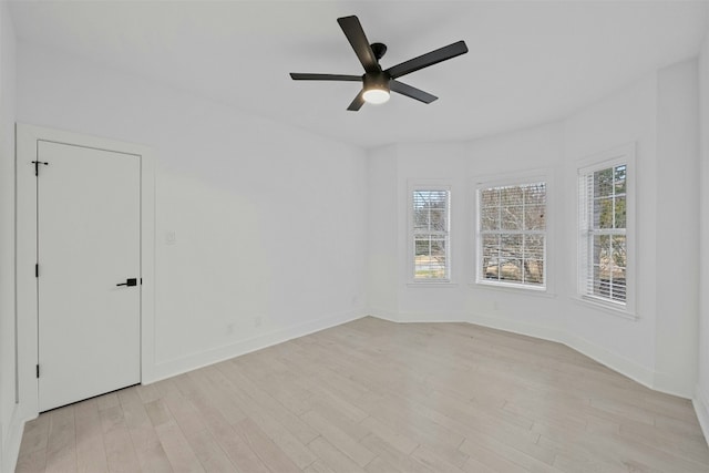spare room featuring baseboards, ceiling fan, and light wood finished floors
