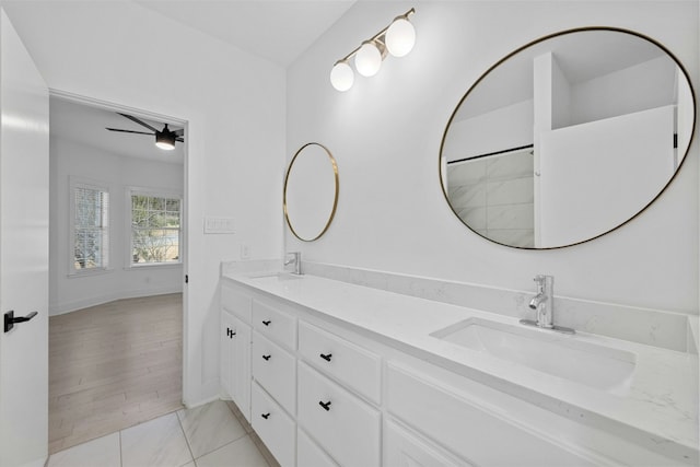 bathroom featuring double vanity, a sink, a ceiling fan, and baseboards