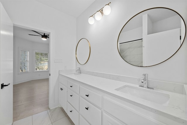 bathroom with a sink, baseboards, ceiling fan, and double vanity
